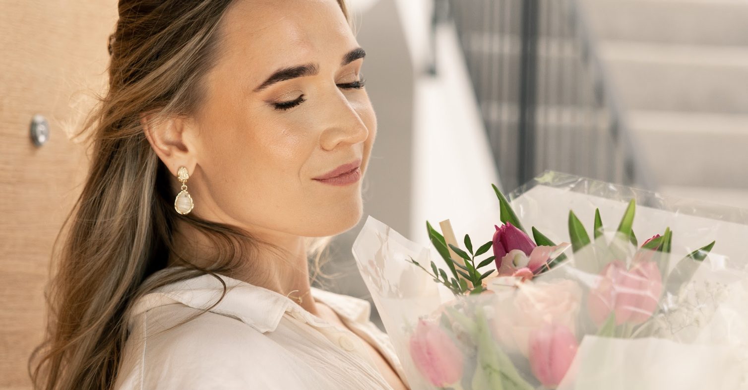 Tess, eyes closed, smiling into a bouquet of pink tulips